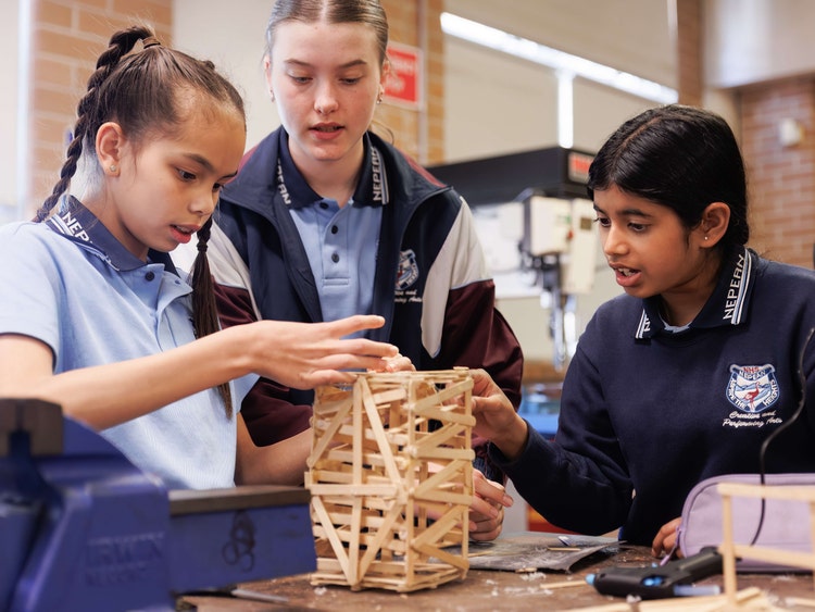 3 students building a tower out of popsicle sticks
