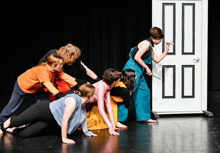 drama students posing in front of door frame on stage